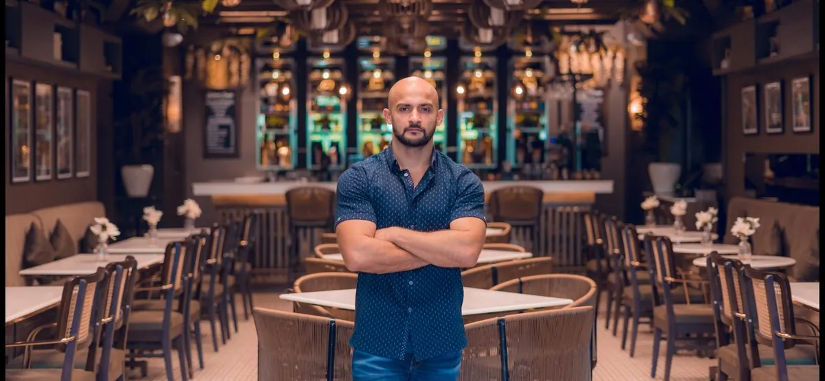 Rish Saini standing in a restaurant dining room, arms folded
